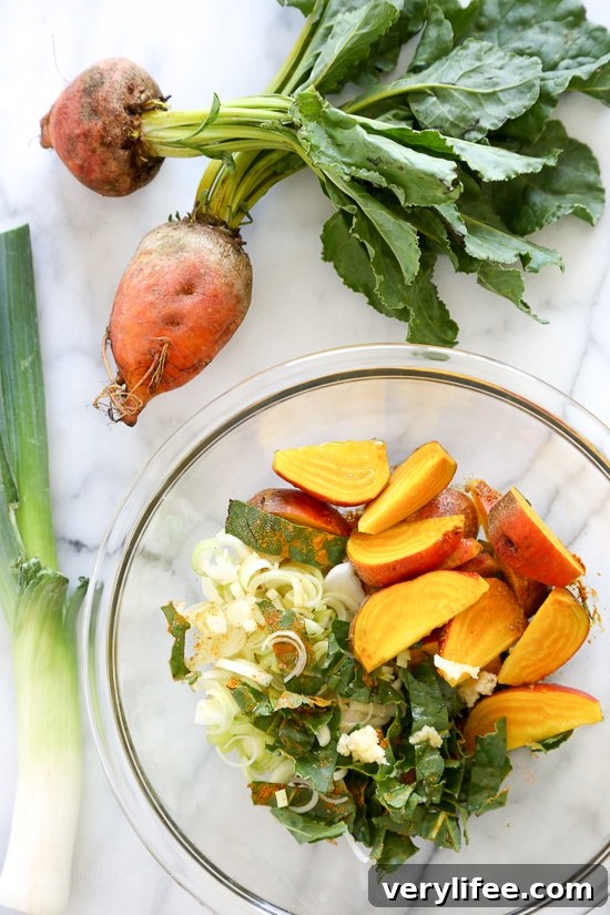 Close-up of turmeric-braised chicken with golden beets and leeks layered in a casserole dish.