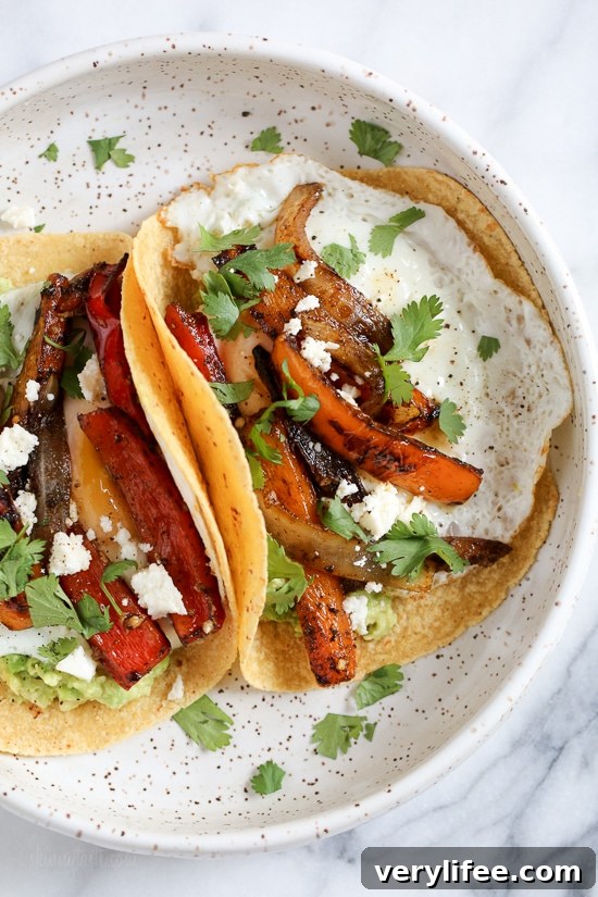 Breakfast fajitas with eggs, peppers, onions, guacamole and a runny egg on top