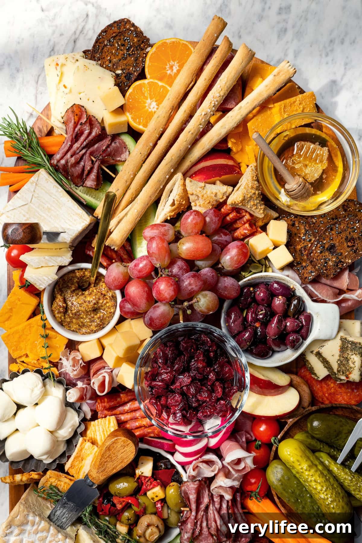 Charcuterie and cheese board with fruit, olives, and spreads.