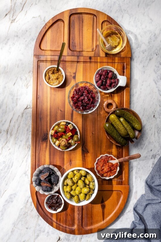 Bowls of spreads, pickles, and olives on wooden charcuterie board.
