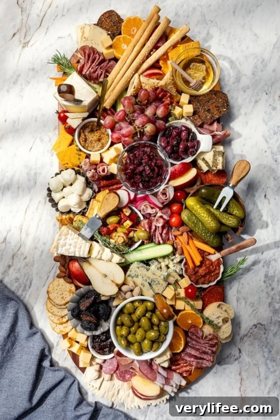 Large charcuterie and cheese board with fruit, pickles, olives, and spreads.