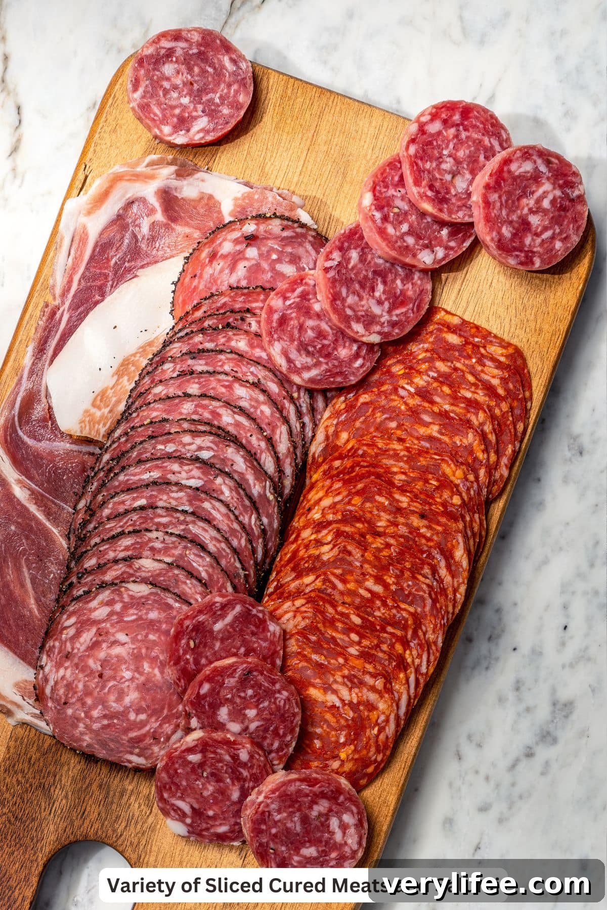 Cured meats and salami on wooden board.