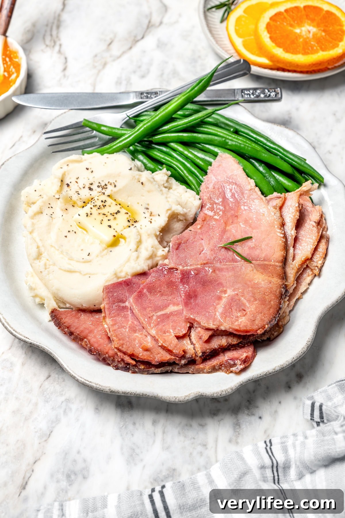 Slices of slow cooker ham Slices of slow cooker ham on plate with mashed potatoes and green beans.