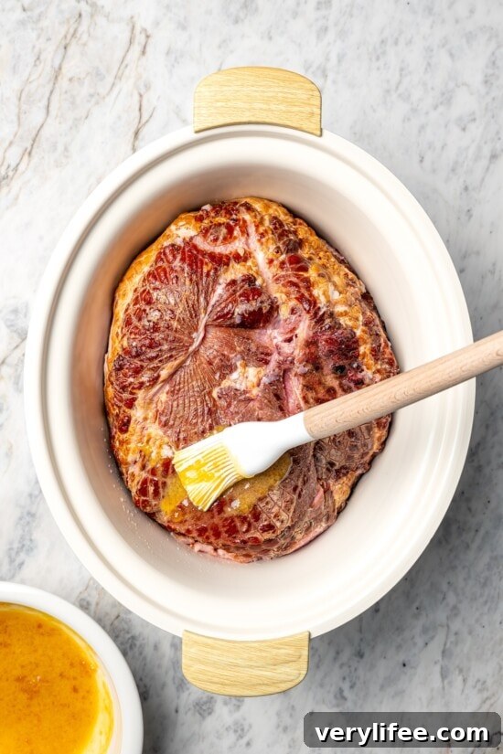 Slow Cooker Apricot Dijon Glazed Ham 6 Brushing glaze onto ham in slow cooker.