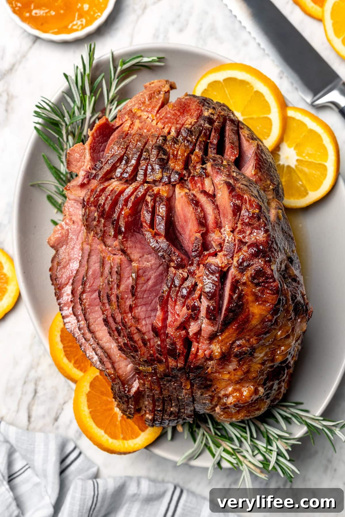 Glazed slow cooker ham Glazed spiral slow cooker ham on platter with rosemary and orange slices.