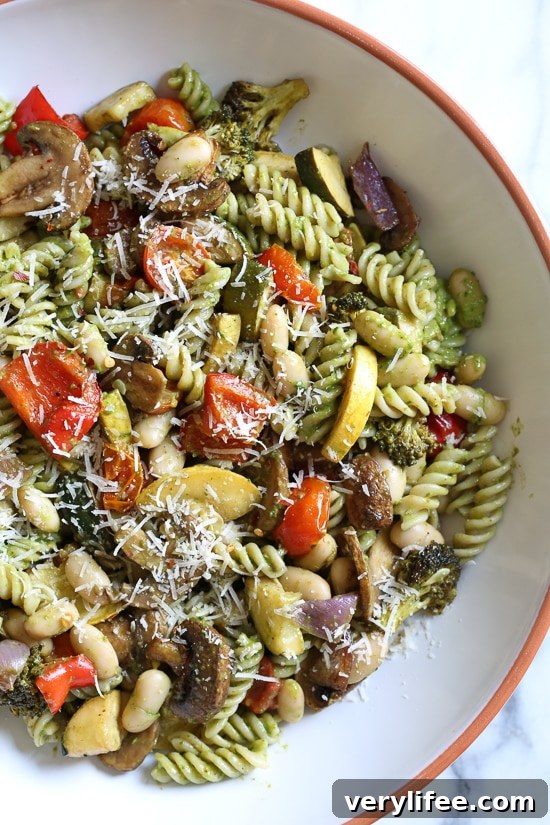 One bite of this Balsamic Roasted Veggie and White Bean Pasta and you'll want to make it all summer long! Roasted zucchini, yellow squash, mushrooms, peppers, and broccoli – loaded with veggies in every bite and finished with pesto and white beans. This is SO good, and picky husband approved!