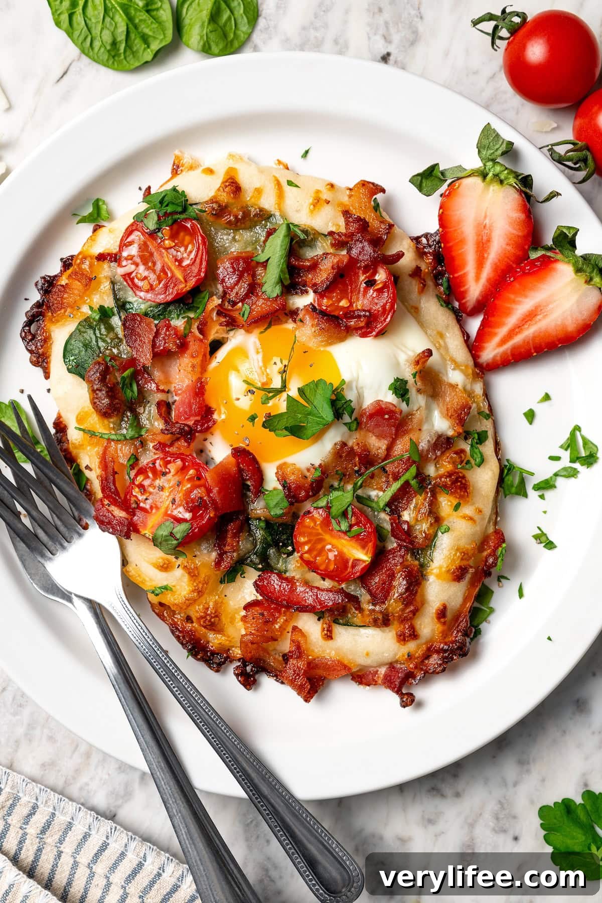 This easy breakfast pizza features a crispy yogurt crust topped with eggs, cheese, spinach and bacon for a savory protein-packed meal. Breakfast pizza with egg, bacon, tomatoes, and spinach on plate.