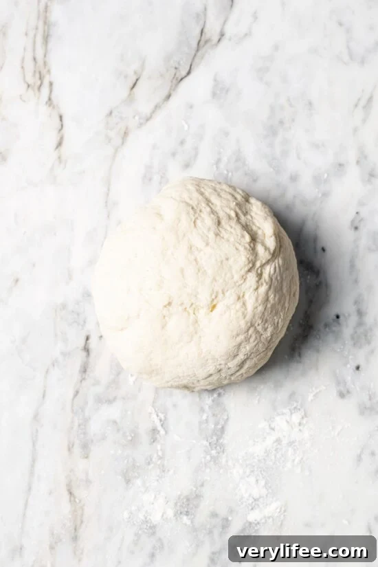 High-Protein Breakfast Pizza Recipe 7 Breakfast pizza dough in ball on floured marble slab.