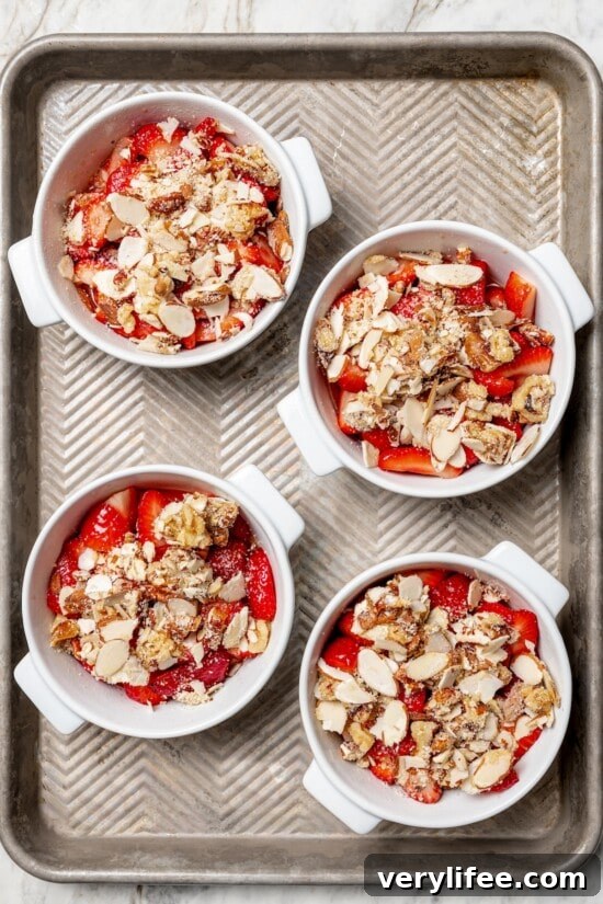 Homemade Strawberry Crisp Recipe with Oat Streusel 8 Overhead view of strawberry crisps in ramekins on baking sheet before baking