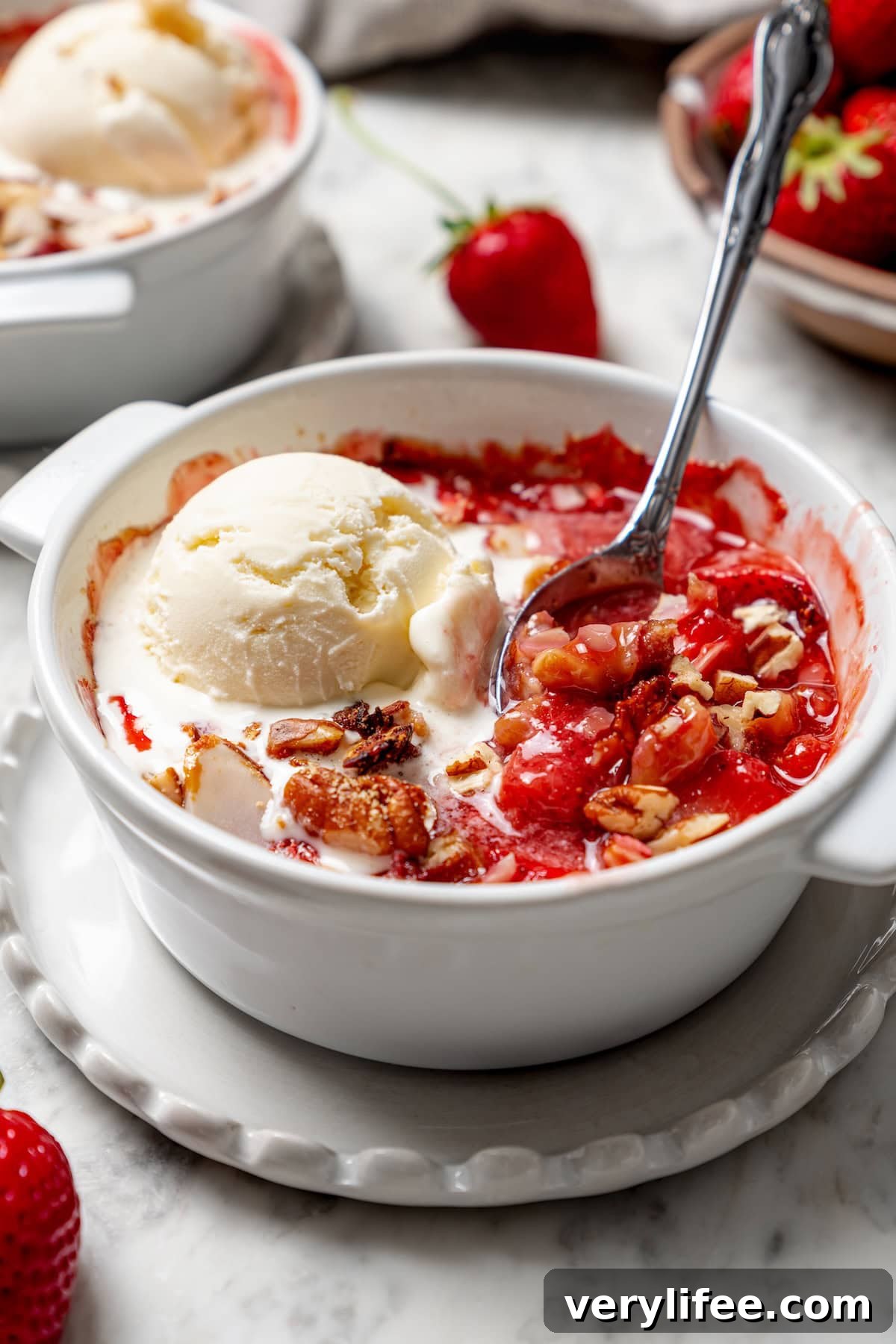 Homemade Strawberry Crisp Recipe with Oat Streusel 10 Spoon digging into healthy strawberry crisp topped with ice cream