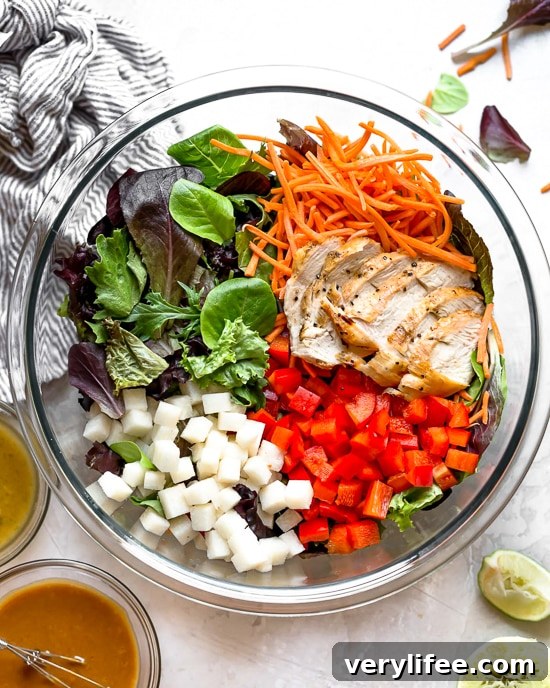 Grilled Chicken Salad with greens and vegetables are tossed in a honey-lime vinaigrette and topped with a delicious peanut sauce.