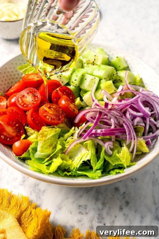 Pouring olive oil over vegetables for Italian chopped salad.