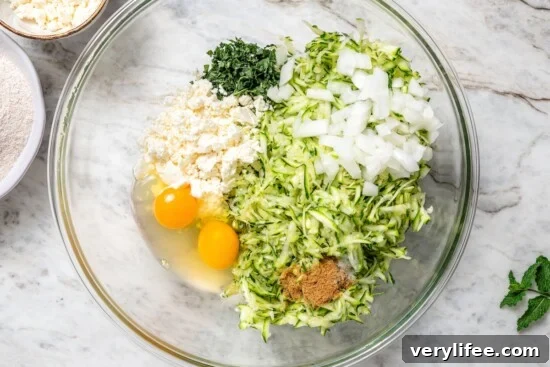 Ingredients for zucchini fritters in bowl before mixing.