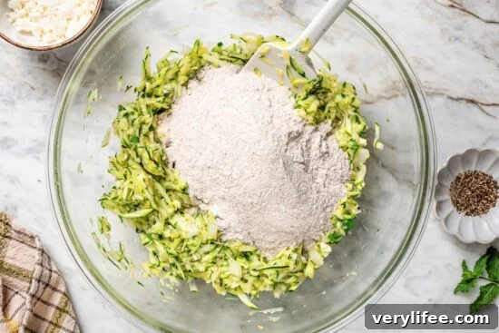 Whole wheat flour added to bowl of shredded zucchini.