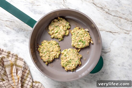 Zucchini fritters in skillet.
