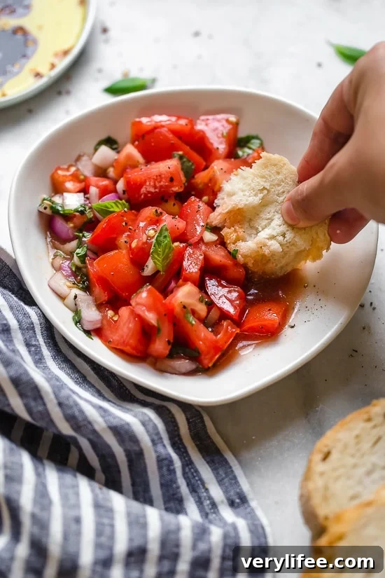 Dipping bread into fresh tomato salad. Dipping bread into bowl of summer tomato salad.