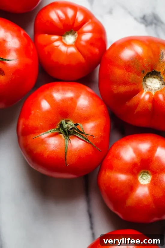 Fresh Summer Tomato Salad with Basil and Olive Oil 4 Ripe beefsteak tomatoes on marble countertop.