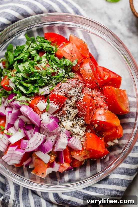 Fresh Summer Tomato Salad with Basil and Olive Oil 5 Ingredients for summer tomato salad in glass bowl.