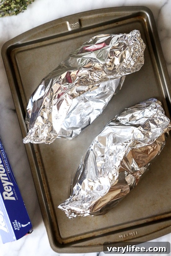 Foil packets of sausage and vegetables ready to bake.