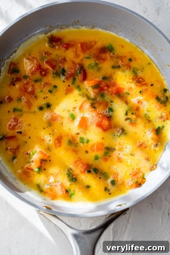 Eggs added to skillet with tomatoes and scallions