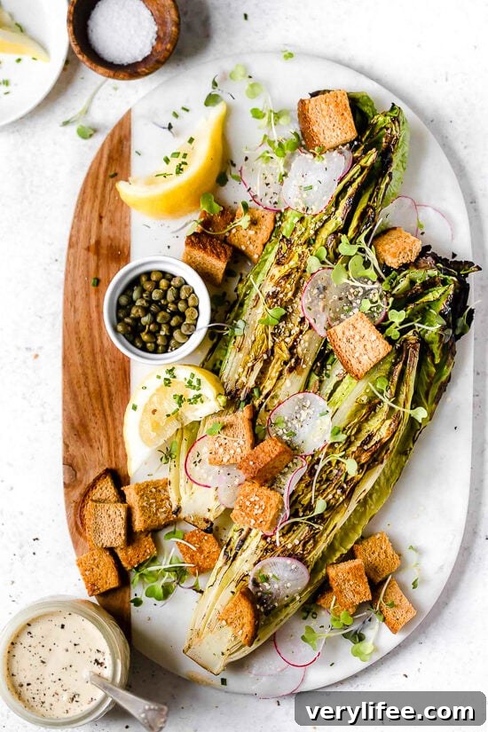 Grilled romaine salad on marble and wood cutting board.