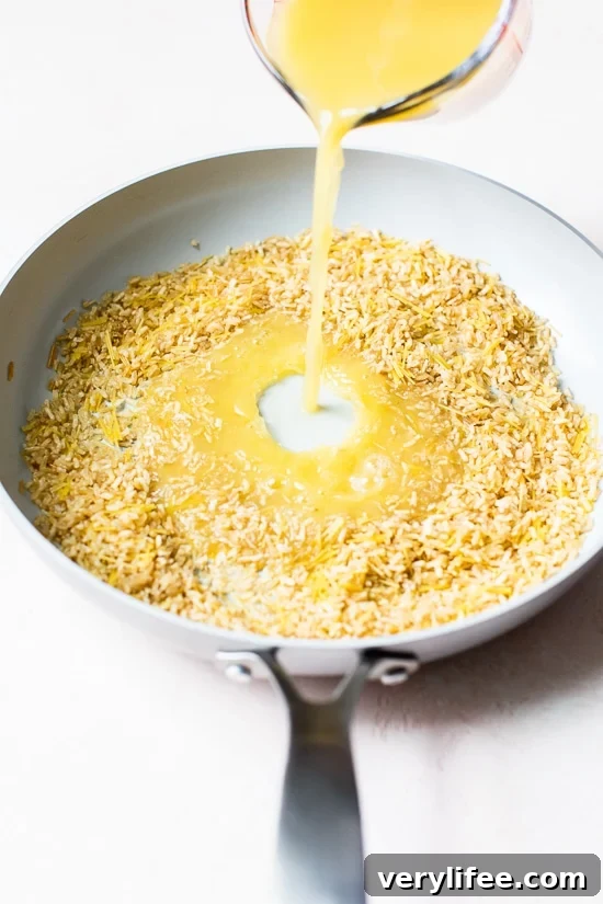 Pouring broth into skillet of rice and pasta for pilaf.