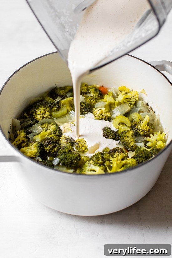 Vegetable Detox Soup Recipe for a Gentle Cleanse 3 Pouring cashew milk into a pot of cooked vegetables.