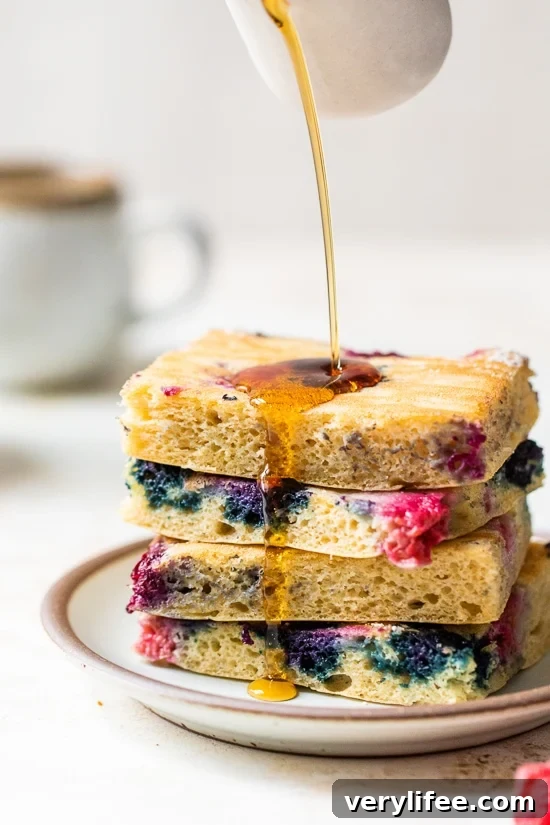 Sheet Pan Yogurt Pancakes with Mixed Berries 3 stacked sheet pan pancakes with syrup