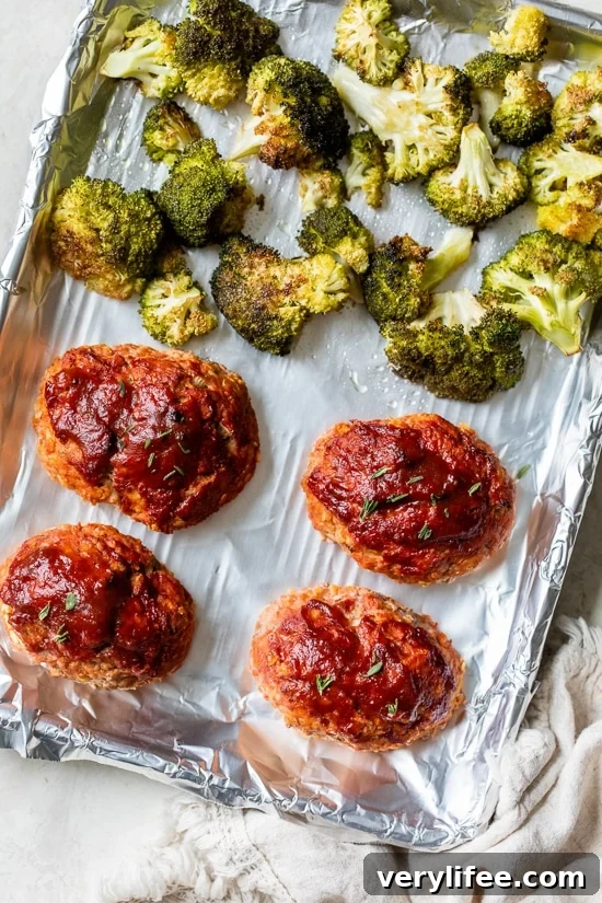 Individual turkey meatloaves baked on a sheet pan with broccoli
