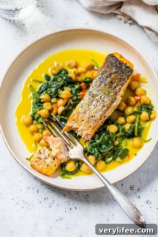 salmon on a plate with a fork, spinach and chickpeas