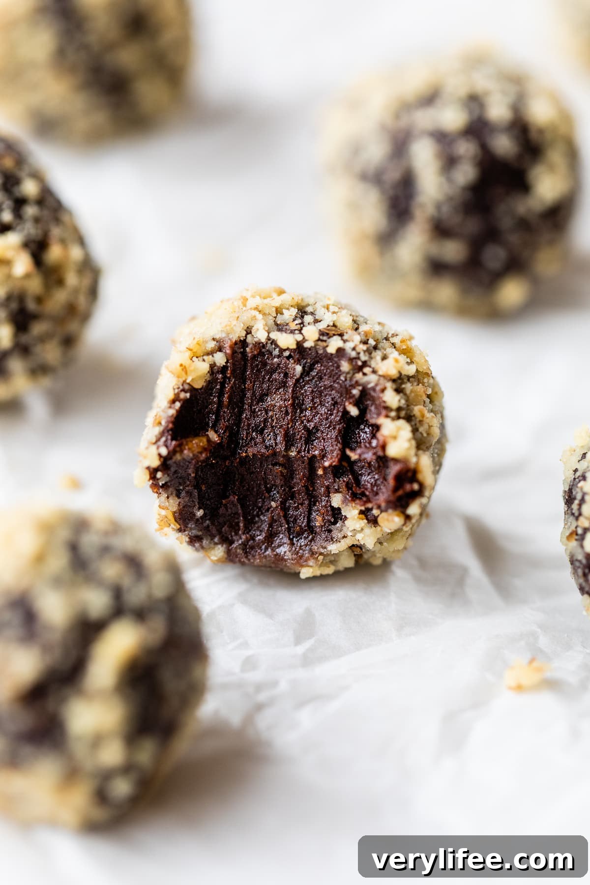 A chocolate date ball with a bite missing to show the fudgy interior
