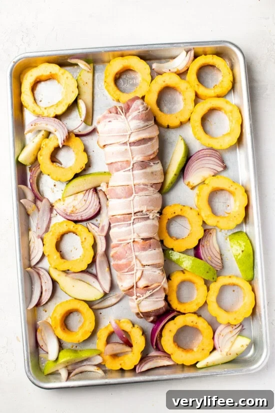 Sheet Pan Bacon-Wrapped Pork Tenderloin Recipe 8 Bacon Wrapped Pork Tenderloin on a sheet pan with fall vegetables